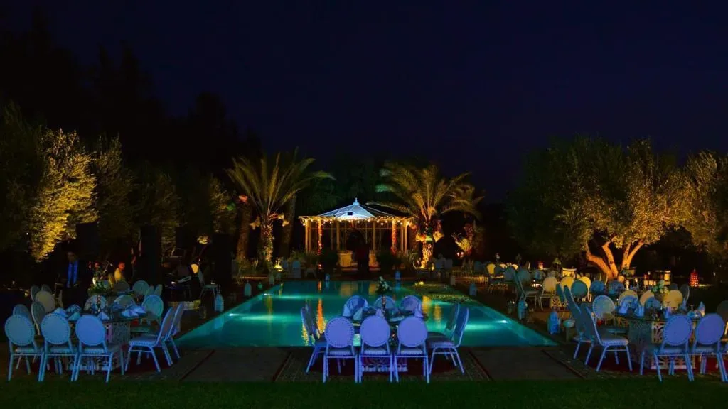 Dîner en plein air au bord de la piscine illuminée, villa avec piscine à Marrakech Quattrocento Palace