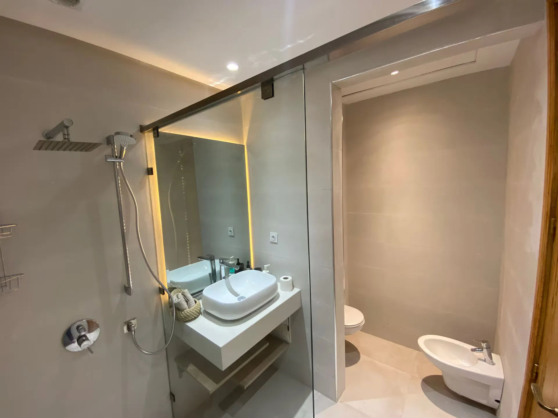 Modern bathroom with walk-in glass shower, vessel sink, and bidet in an apartment with pool in Marrakech