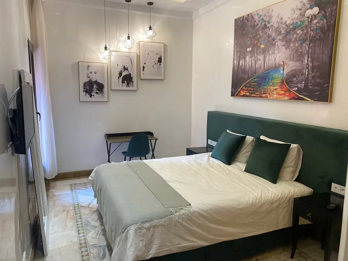 Modern master bedroom with double bed, desk area, and TV in an apartment with pool in Marrakech