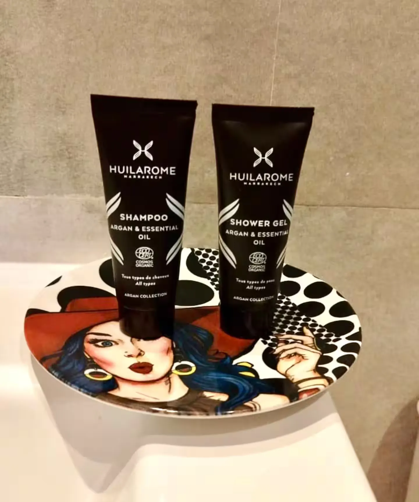 Organic Huilarome toiletries displayed on an artistic dish in a palm grove apartment