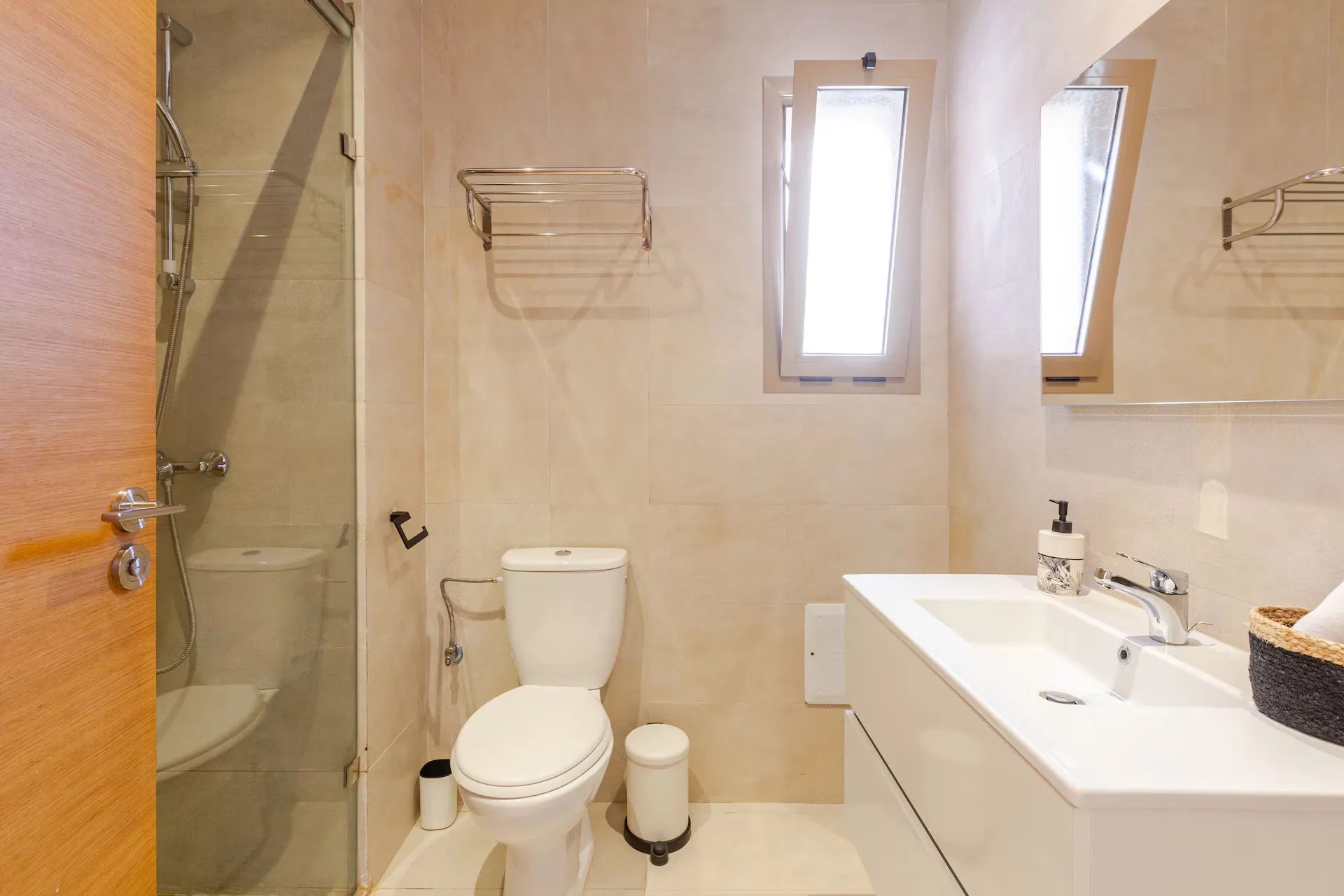 Modern bathroom featuring a glass walk-in shower and white vanity in a palm grove apartment