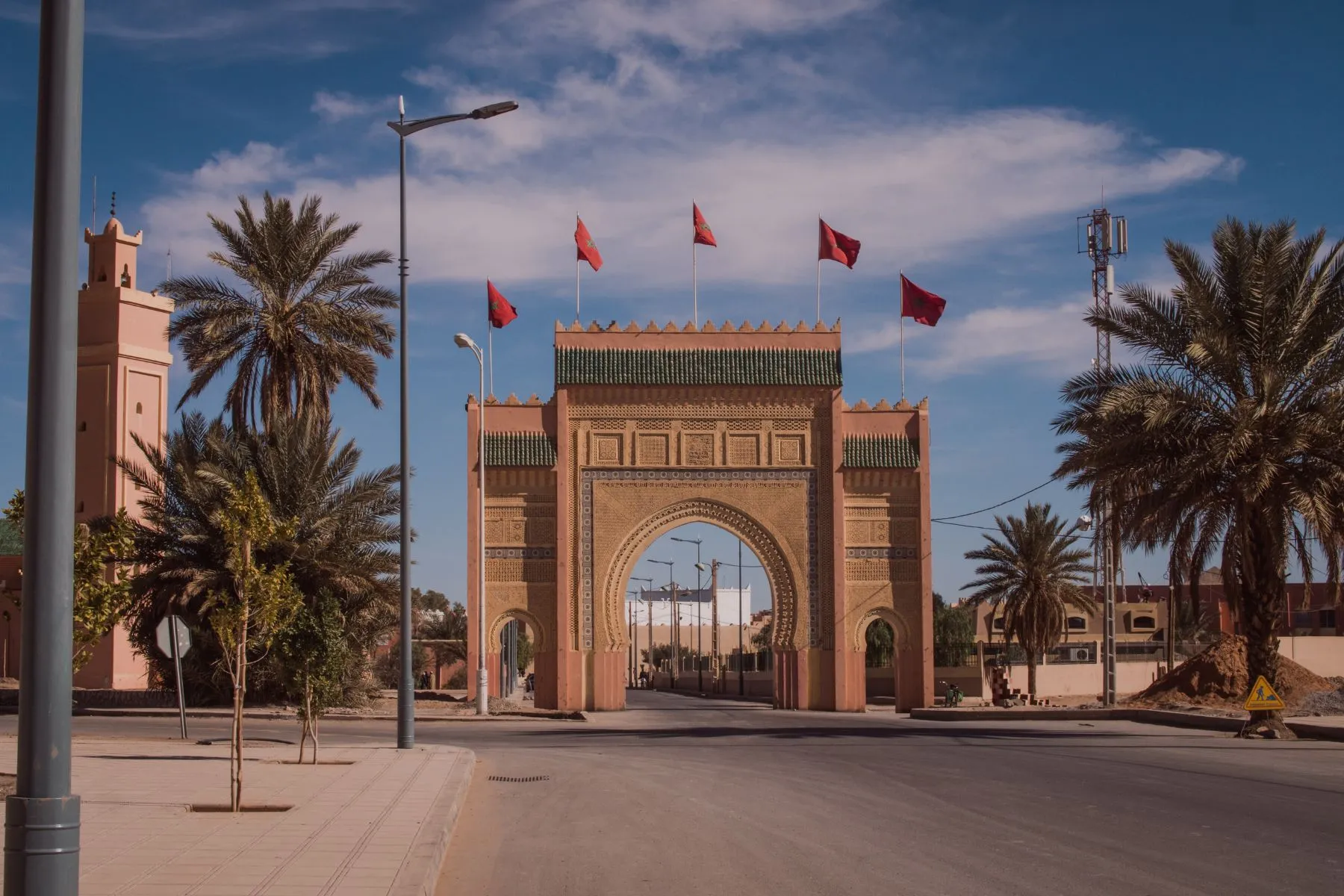 Marrakech city gate with-Moroccan flags and palm trees